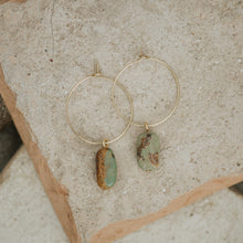 Load image into Gallery viewer, Gold hoop earrings with green stone pendants on a stone surface