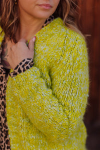 Person wearing a bright yellow textured sweater with a blurred background