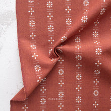 Load image into Gallery viewer, Brown fabric with white floral patterns on a textured surface