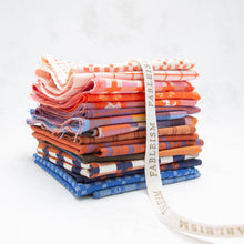 Load image into Gallery viewer, Stack of colorful fabric bundles with a visible brand ribbon on a white background