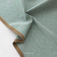 Green fabric with a subtle pattern on a white background, featuring the brand 'Fableism'.