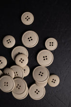 Load image into Gallery viewer, Beige buttons scattered on a dark surface