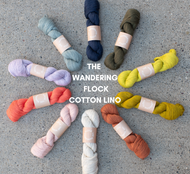 Assorted skeins of yarn arranged in a circle on a concrete surface with 'The Wandering Flock Cotton Lino' text.