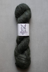 Dark gray skein of yarn with a label on a gray background
