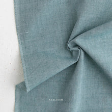Load image into Gallery viewer, Close-up of teal fabric with 'Fableism' branding on a light background