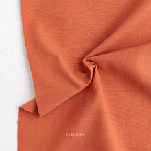 Load image into Gallery viewer, Close-up of orange fabric with 'Fableism' branding on a white background
